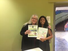 photo of two women holding, one holding a flyer and one holding a book